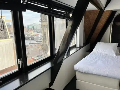 a bedroom with a bed and windows with a view at Sotel Amsterdam Central Station in Amsterdam