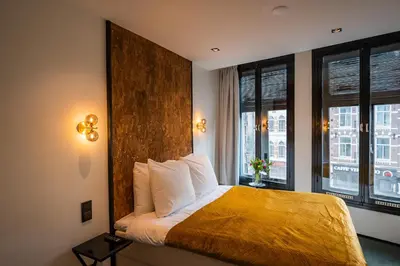 a hotel room with a bed and two windows at Sotel Amsterdam Central Station in Amsterdam