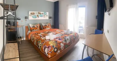 a bedroom with a bed with an orange comforter at SEA MORE in Zandvoort
