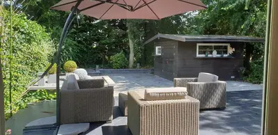 a group of chairs and an umbrella on a patio at Lake House 74, luxury accommodation ir Sauna in Warmond