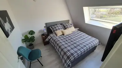 a bedroom with a bed and a blue chair at Lake House 74, luxury accommodation ir Sauna in Warmond