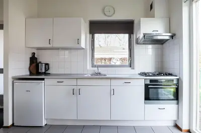 a white kitchen with white cabinets and a window at Zilt vakantiehuisje - Rekerlanden 283 in Schoorldam