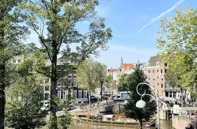 a river with boats in a city with buildings at Little Tulip in Amsterdam