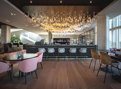 a restaurant with a bar with pink chairs and a chandelier at Van der Valk Hotel Amsterdam Zuidas-Rai in Amsterdam