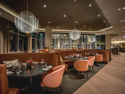 a restaurant with tables and chairs and chandeliers at Van der Valk Hotel Amsterdam Zuidas-Rai in Amsterdam
