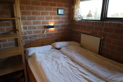 a bed in a room with a brick wall at Rekerlanden 161 in Schoorldam