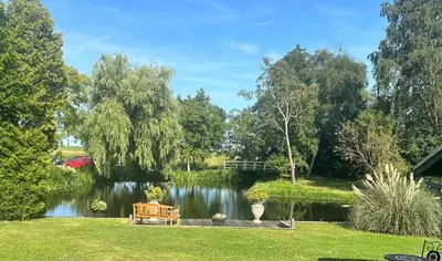 a park with a bench next to a lake at De Weideblom in Schermerhorn