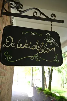 a sign hanging from the side of a building at De Weideblom in Schermerhorn