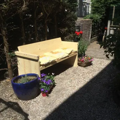 a wooden bench sitting on the ground next to some flowers at Familie Quellhorst in Leiden