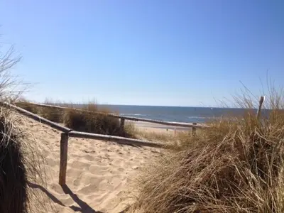 a sandy path to a beach with the ocean at Westenwind in Egmond aan Zee