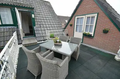 a patio with a table and chairs on a balcony at Westenwind in Egmond aan Zee