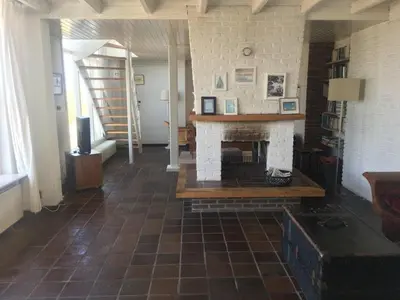 a living room with a fireplace and a staircase at Pacific, spectacular seaview in Bergen aan Zee