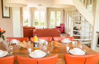 a dining room with a table and orange chairs at Bungalow 6p in Noordwijk