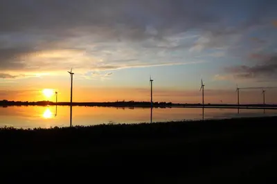 a group of windmills in the water at sunset at Vakantiepark Zijpersluis in Burgerbrug
