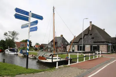 a boat docked next to a house with street signs at Vakantiepark Zijpersluis in Burgerbrug