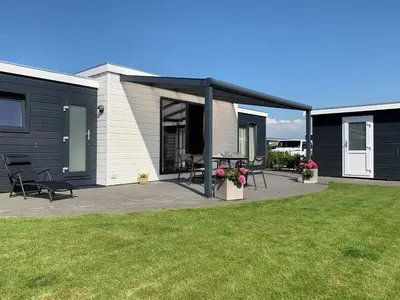 a house with a patio with a table and chairs at Vakantiepark Zijpersluis in Burgerbrug