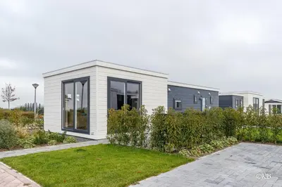 a small white building with windows and a yard at Vakantiepark Zijpersluis in Burgerbrug