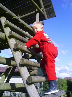 a young boy climbing up a wooden ladder at Vakantiepark Zijpersluis in Burgerbrug