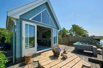 a small blue house with a wooden deck and a table at Romantic Dutch hideaway in Jisp