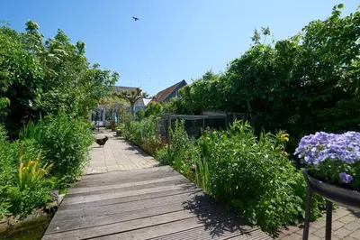 a wooden path through a garden with flowers and plants at Romantic Dutch hideaway in Jisp