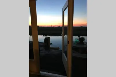 a view of a sunset through a glass door at Romantic Dutch hideaway in Jisp