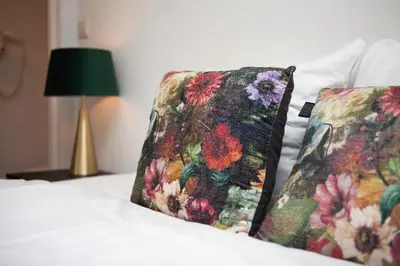 a bed with two pillows on it with a lamp at King's Inn City Hotel Alkmaar in Alkmaar