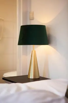 a gold lamp on a table next to a bed at King's Inn City Hotel Alkmaar in Alkmaar