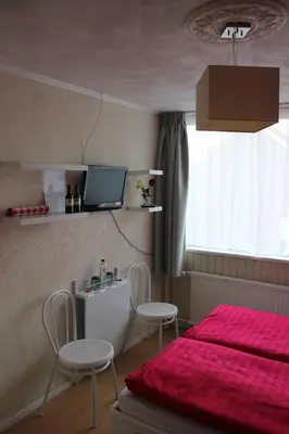 a bedroom with a bed and two chairs and a tv at Kerstins Bed and Breakfast in Egmond aan Zee
