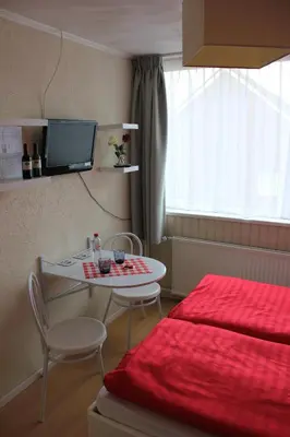 a room with a bed and a table and a tv at Kerstins Bed and Breakfast in Egmond aan Zee