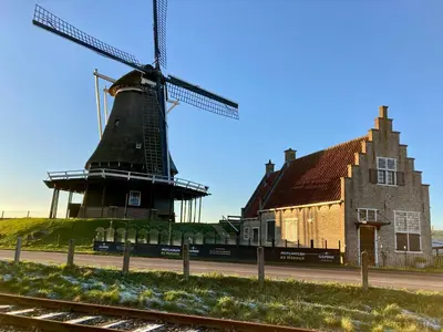 an old windmill next to a building and a house at Landelijk gelegen houten huisje in Opperdoes