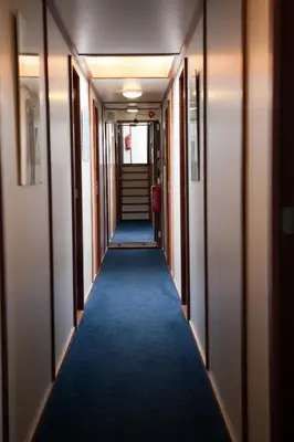 a long hallway with a blue carpet and stairs at Hotelboat Sarah in Amsterdam