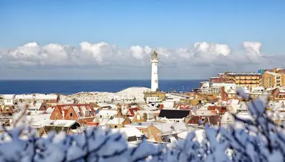 a white lighthouse in a city with a town with houses at Zomerhuis Simoons in Egmond aan Zee