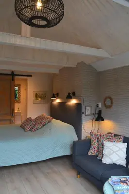 a bedroom with a bed and a couch at Studio Clematis Bergen in Bergen