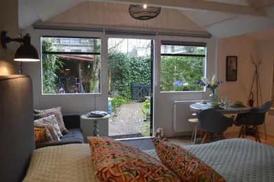 a living room with a bed and a sliding glass door at Studio Clematis Bergen in Bergen