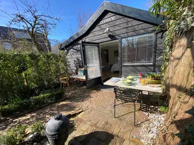 a small shed with a table and a patio at Studio Clematis Bergen in Bergen