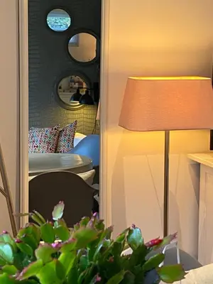 a living room with a lamp and a bedroom at Studio Clematis Bergen in Bergen