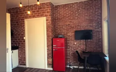 a brick wall with a red refrigerator next to a door at Queens Beachhouse in Zandvoort