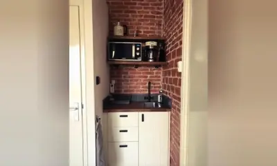 a kitchen with white cabinets and a brick wall at Queens Beachhouse in Zandvoort