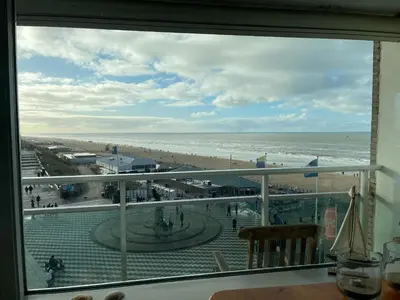 a view of the beach from a room with a window at Happy Beach Apartment in Zandvoort