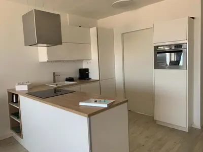 a white kitchen with a counter and a refrigerator at Happy Beach Apartment in Zandvoort