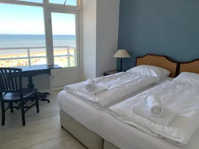 two beds in a bedroom with a view of the beach at Happy Beach Apartment in Zandvoort