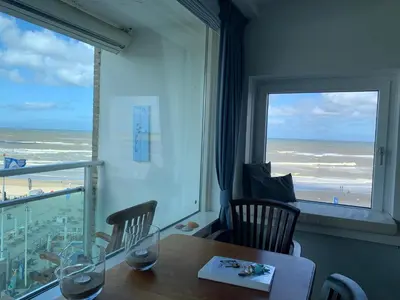 a dining room with a table and a view of the ocean at Happy Beach Apartment in Zandvoort