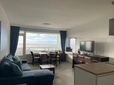 a living room with a couch and a tv and a table at Happy Beach Apartment in Zandvoort