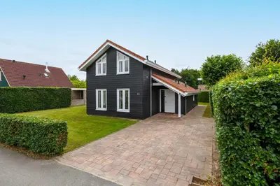 a black house with white windows and a brick driveway at The Black House - Luxurious Holiday Villa Zeewolde in Zeewolde