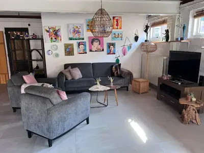 a living room with a couch and a tv at Finca Noordwijk met privé tuin, dichtbij strand in Noordwijk