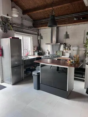 a kitchen with stainless steel appliances and a wooden table at Finca Noordwijk met privé tuin, dichtbij strand in Noordwijk
