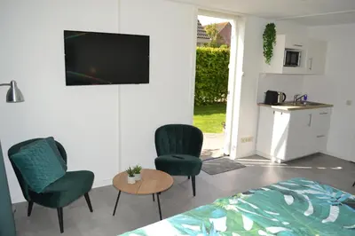 a bedroom with two chairs and a table and a tv at Studio 38 in Zandvoort