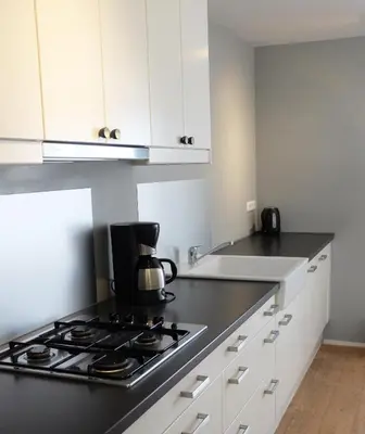 a kitchen with white cabinets and a stove top oven at Kuta Beach in Zandvoort