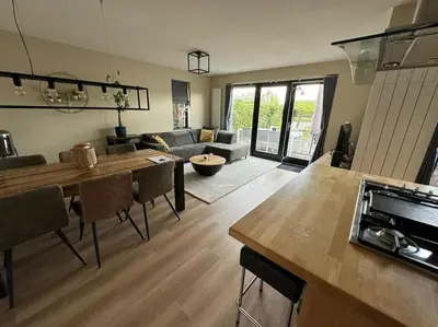 a kitchen and living room with a table and a couch at Vakantiehuis aan het water in Vinkeveen