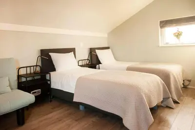 a bedroom with two beds and a chair and a window at Vakantiehuis aan het water in Vinkeveen
